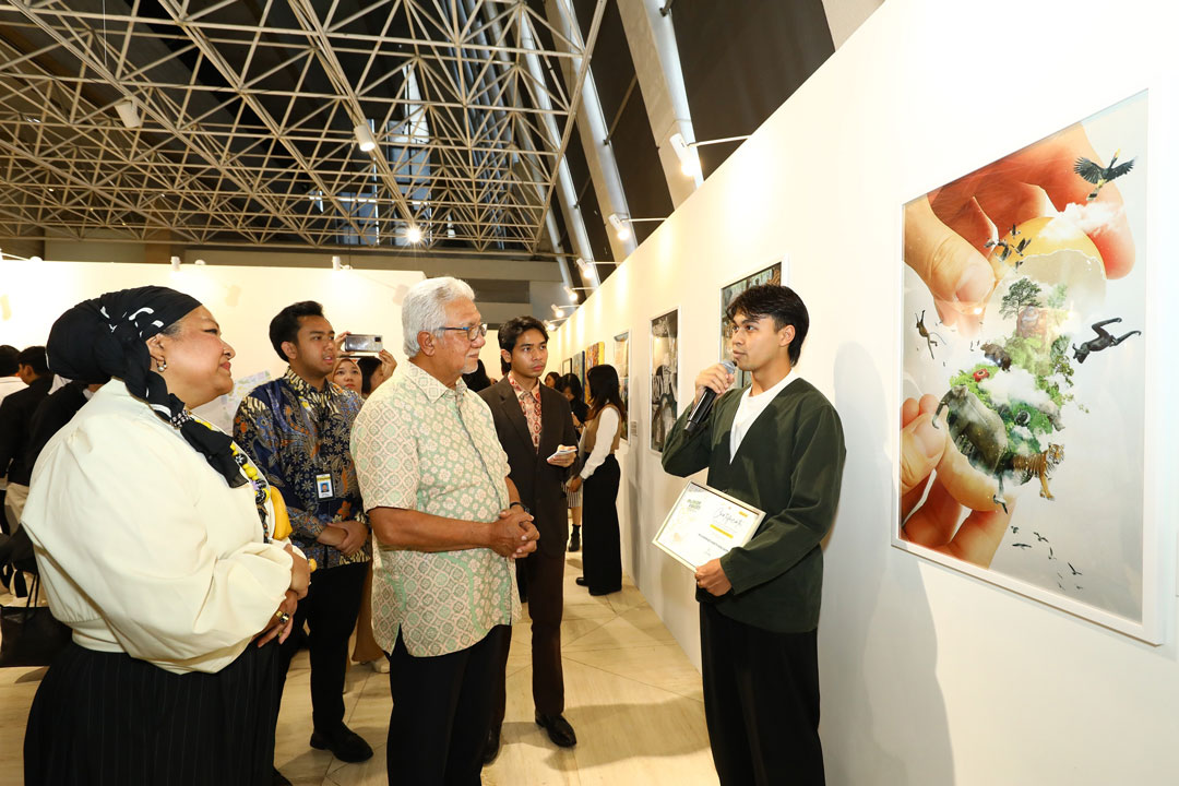 Muhammad Harith Zafran from Universiti Teknologi MARA Puncak Alam, the First Prize winner in the University (Photo Imaging) category, shares the inspiration behind his winning piece ‘Reborn’ to Tan Sri Dato' Sri Ir. Zamzamzairani Mohd Isa, Chairman of Maybank & Maybank Foundation (in bright batik) and Izlyn Ramli, Head Group Corporate Affairs Maybank & CEO of Maybank Foundation (in white). The artist highlighted that the artwork was inspired by Maybank’s TIGER value of Growth and the Quranic verse from Surah An-Nur (24:45), which reflects the divine origin and diversity of life.